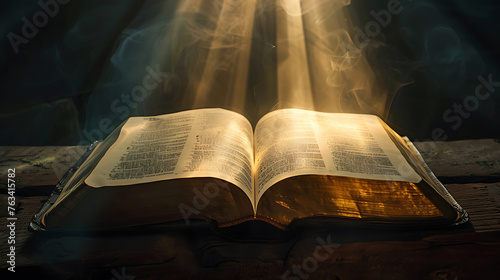 Open holy bible with light rays coming out of the pages on wooden background