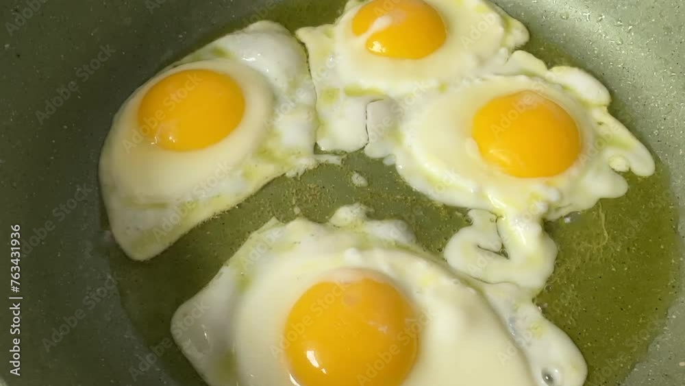 Chicken eggs in a frying pan while frying on stove. Cooking an omelet and scrambled eggs from a chicken egg. Natural organic eggs in cardboard package on table in kitchen. Eggs for breakfast. Chicken eggs in a frying pan while frying on stove. Cooking an omelet and scrambled eggs from a chicken egg. Natural organic eggs in cardboard package on table in kitchen. Eggs for breakfast.