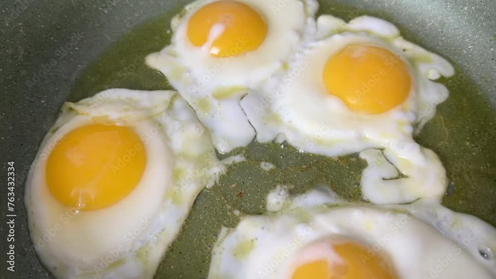 Chicken eggs in a frying pan while frying on stove. Cooking an omelet and scrambled eggs from a chicken egg. Natural organic eggs in cardboard package on table in kitchen. Eggs for breakfast. Chicken eggs in a frying pan while frying on stove. Cooking an omelet and scrambled eggs from a chicken egg. Natural organic eggs in cardboard package on table in kitchen. Eggs for breakfast.