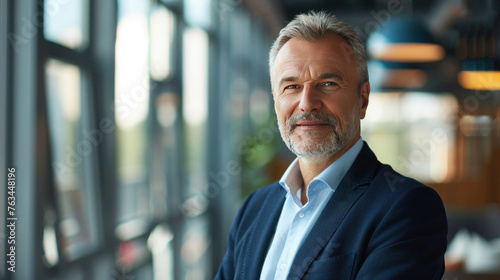 Mature 55 year old confident businessman executive standing in office looking at camera