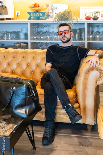 A young man sitting on a sitting on a sofa in a cafe photo