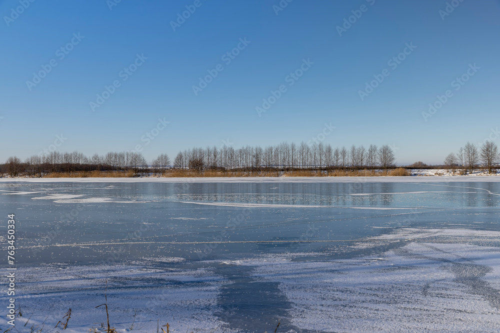 frozen lake covered with snow and ice in winter