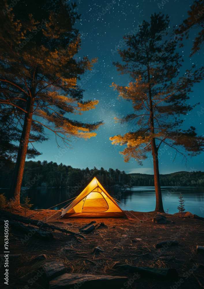 Illuminated tent at lakeside campsite. Night time. Outdoor adventures. Camping. Traveling.