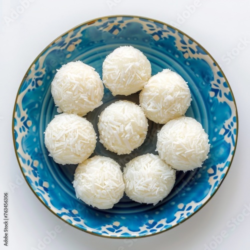 Homemade coconut bites on a blue ceramic plate on a white background, Indian traditional sweets, Diwali laddu, holi, coconut laddoo