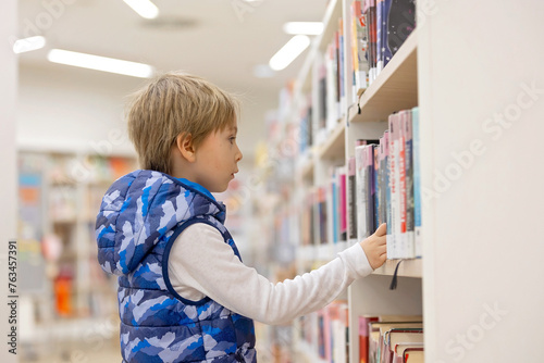 Smart child, school boy, educating himself in a library, borrowing books