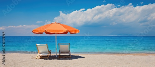 Two chairs and an umbrella on sandy beach