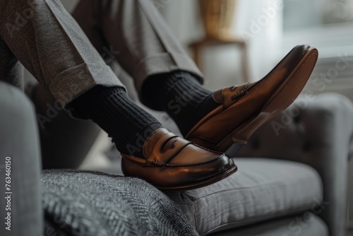 A person is casually seated on a couch, wearing brown shoes