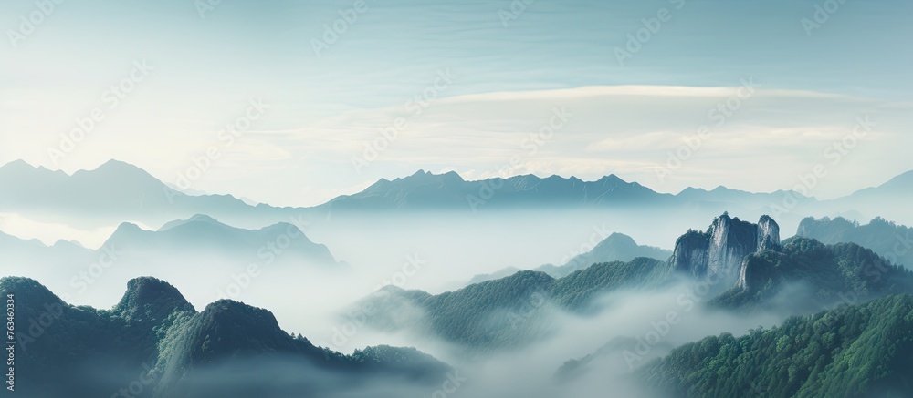 Majestic mountains shrouded in mist under a clear blue sky