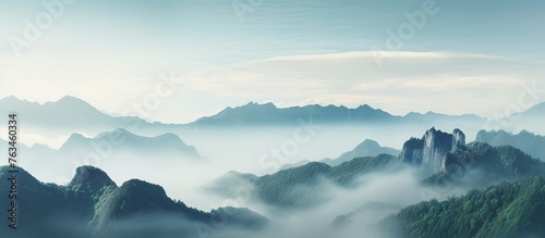 Majestic mountains shrouded in mist under a clear blue sky