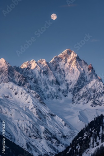 A snow-covered mountain under a full moon in the night sky