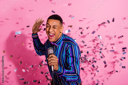 Photo of funky flirty guy wear striped shirt singing microphone winking you eye isolated pink color background photo