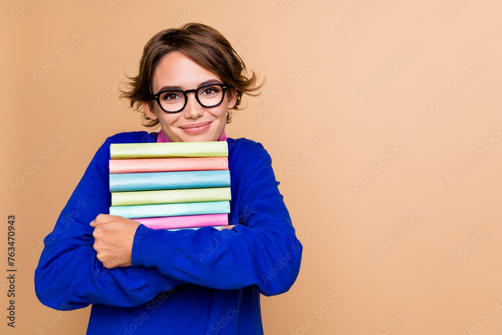 Portrait of clever pretty girl arms hold hug pile stack book empty space isolated on beige color background Portrait of clever pretty girl arms hold hug pile stack book empty space isolated on beige color background