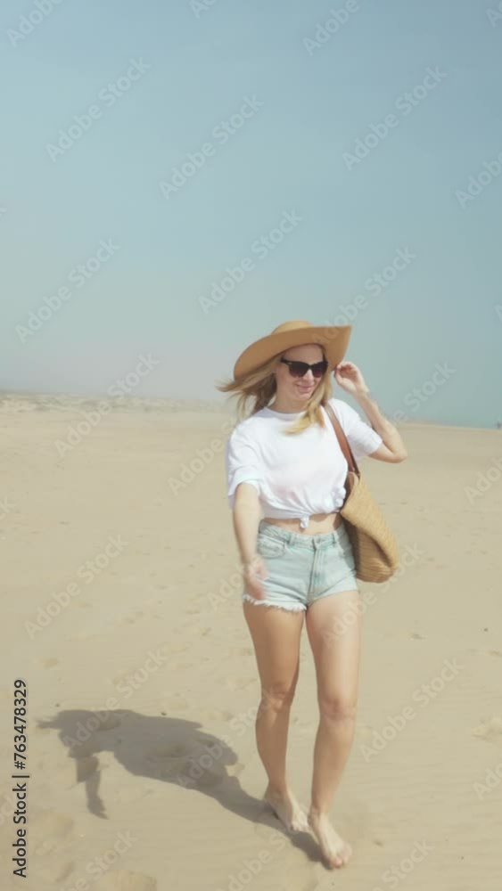 Girl walk along beach in denim shorts, white t-shirt, and straw hat near sea, embody concept of leisurely summer stroll and vacation. Vertical Girl walk along beach in denim shorts, white t-shirt, and straw hat near sea, embody concept of leisurely summer stroll and vacation. Vertical