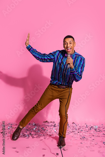 Full length vertical photo of impressed positive guy dressed striped shirt enjoying karaoke isolated pink color background photo