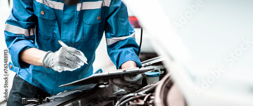 Car care maintenance and servicing, Close-up hand technician auto mechanic checking inspection list after repairing change spare part car engine problem and car insurance service.