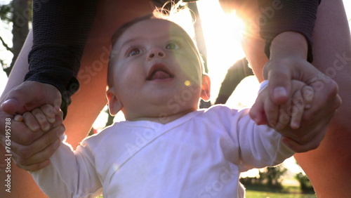 Mother holding baby child outside during sunset helping to stand up learnign to walk photo