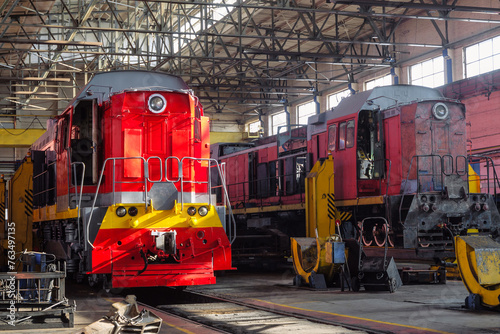 Red traction locomotives on serviced at a repair depot. Locomotive on fixed jacking units.