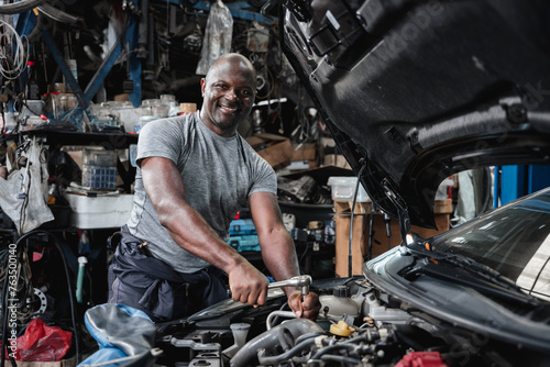 A man is smiling while working on a car engine