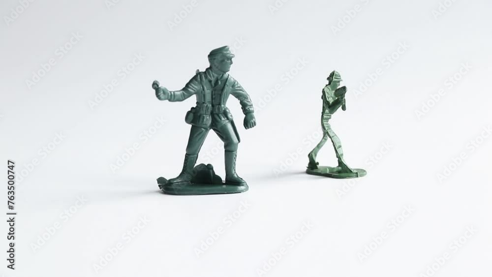 Female hand arranging green plastic soldiers on white Female hand arranging green plastic soldiers on white