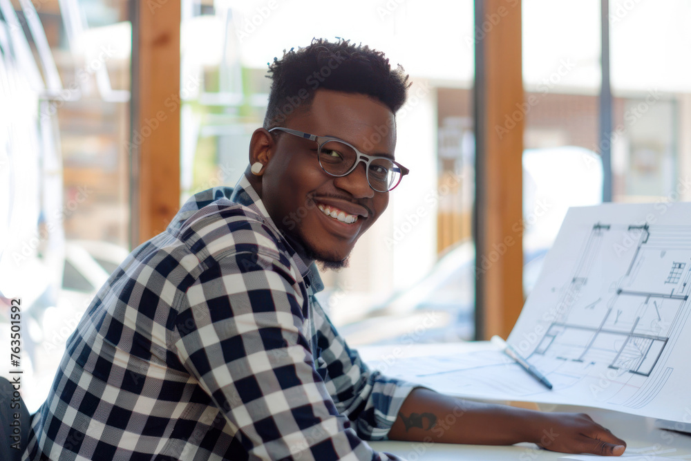 Young creative designer with glasses reviews architectural plans in an office