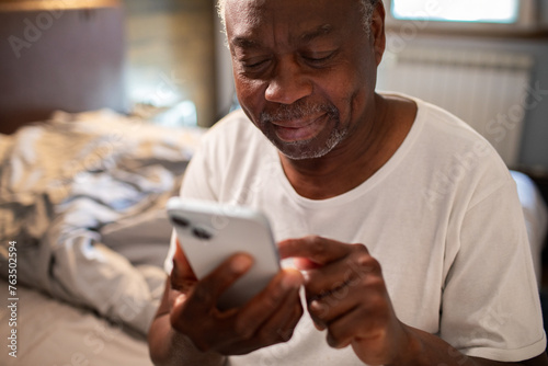 Senior man using smartphone at home photo