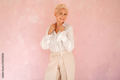 Portrait of a blonde, short hairstyle woman looking at the camera with gentle smile. Mature woman feeling calm and happy.