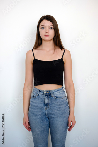 Young girl in black t-shirt and blue jeans model snap front look on white background