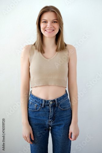 Young smiling girl model snap in beige top t-shirt front look on white background