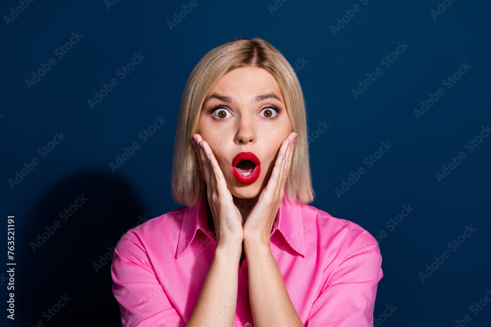 Photo of speechless girl with bob hairdo dressed pink shirt hold hands on cheekbones staring isolated on dark blue color background Photo of speechless girl with bob hairdo dressed pink shirt hold hands on cheekbones staring isolated on dark blue color background