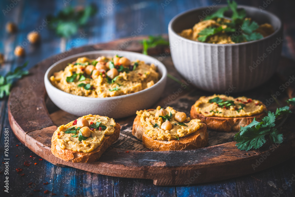 Hummus, chickpea puree in a bowl and on toasted bread slices Hummus, chickpea puree in a bowl and on toasted bread slices