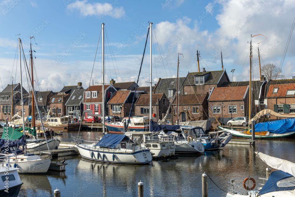 Spakenburg, the Netherlands. 25 February 2024. A harbor with boats and typical Spakenburg houses in the background on a cloudy day.