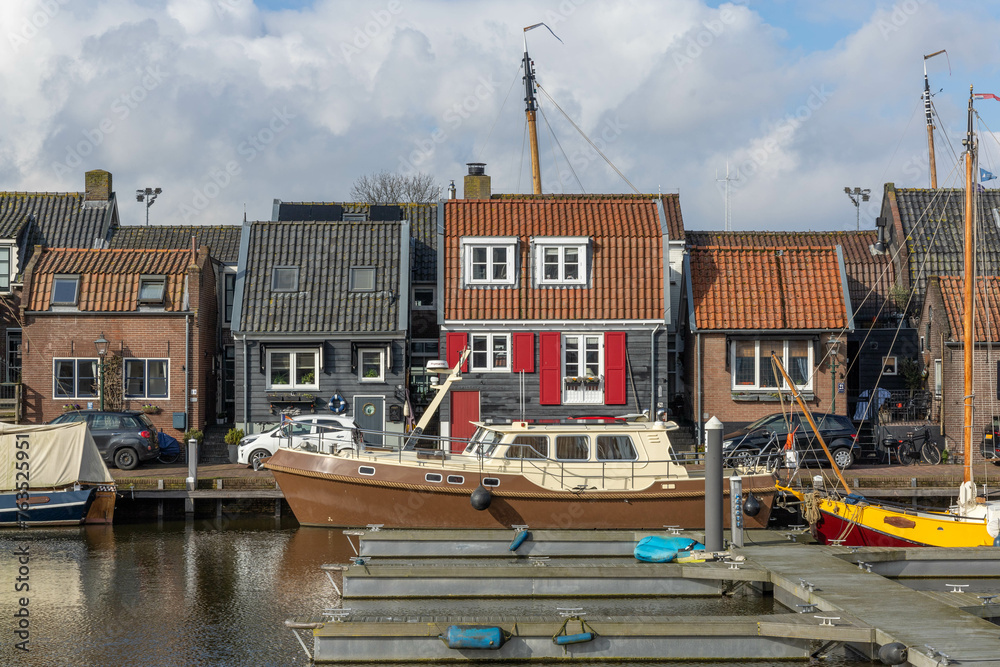 Spakenburg, the Netherlands. 25 February 2024. A harbor with boats and typical Spakenburg houses in the background on a cloudy day.