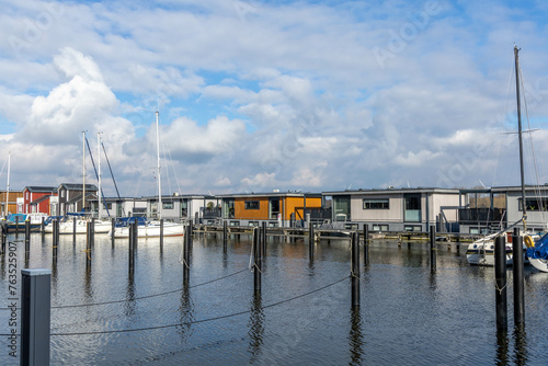 Spakenburg, the Netherlands. 25 February 2024. A harbor with houseboats equipped with solar panels and windmills in the background on a cloudy day.