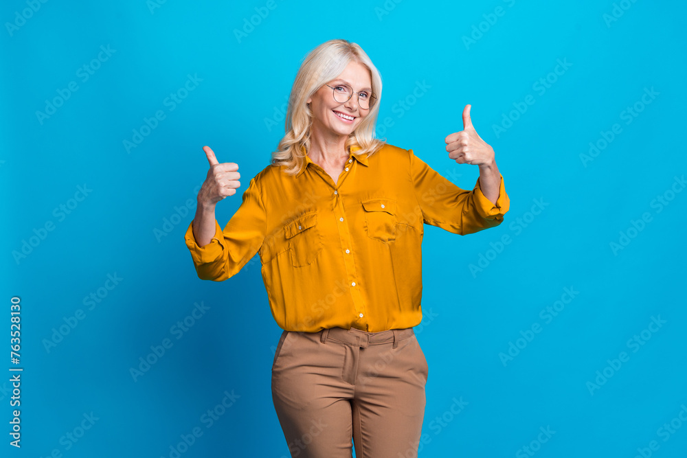 Photo portrait of pretty pensioner female showing thumb up wear trendy orange smart casual outfit isolated on blue color background