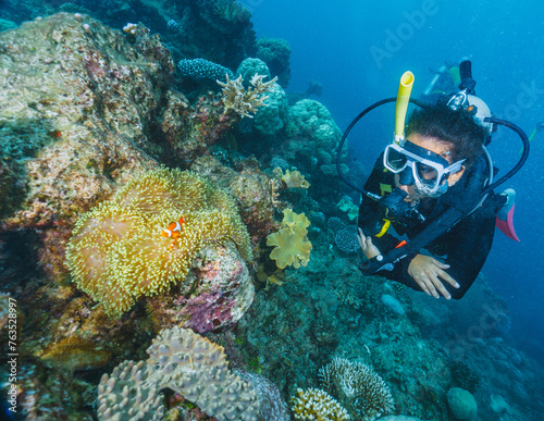 Fototapeta Naklejka Na Ścianę i Meble -  A woman is scuba diving in the ocean and is surrounded by coral