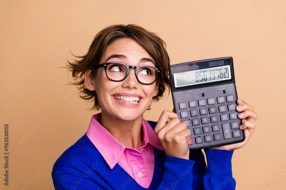 Photo portrait of pretty young girl look excited calculator wear trendy blue outfit isolated on beige color background Photo portrait of pretty young girl look excited calculator wear trendy blue outfit isolated on beige color background