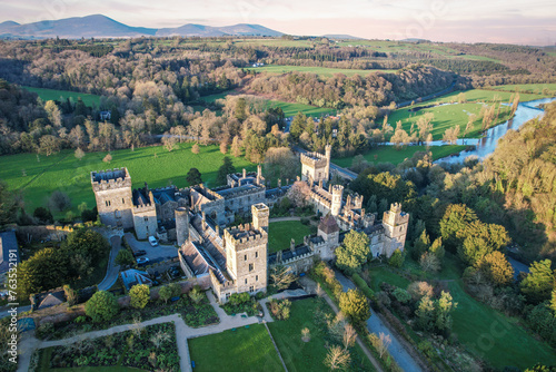 Aerial view of majestic Lismore Castle in County Waterford, Ireland, bathed in the golden glow of the setting sun on the first day of spring, showcasing its timeless beauty and historic charm photo