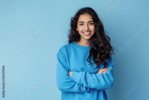 portrait of happy beautiful woman in blue sweater standing with arms crossed