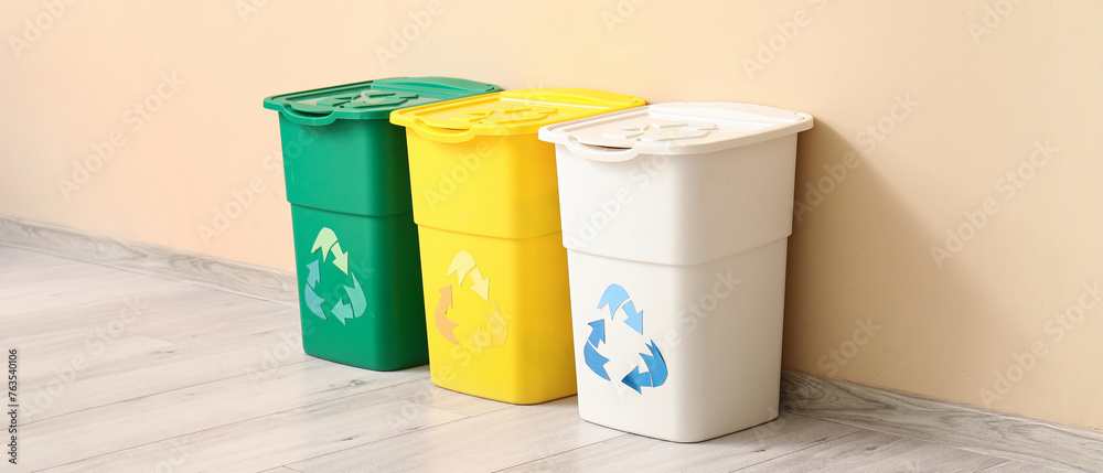 Containers for garbage near beige wall. Recycling concept - obrazy, fototapety, plakaty 