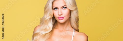 Beautiful woman with long blonde hair on yellow background. Hair care and beauty concept. Copy space © firax