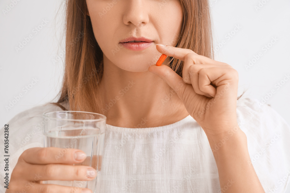 Beautiful woman with vitamin supplement and glass of water on grey background, closeup Beautiful woman with vitamin supplement and glass of water on grey background, closeup
