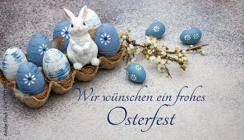 Osterhase sitzt auf Ostereiern mit der Beschriftung wir wünschen ein frohes Osterfest.