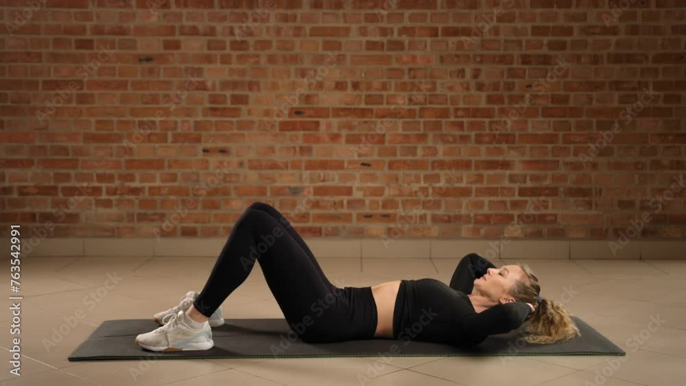 Engaging the core, a fitness expert executes crunches with precision on a gym mat, enhancing abdominal muscle strength against the textured backdrop of a red brick wall. Camera 8K RAW. Engaging the core, a fitness expert executes crunches with precision on a gym mat, enhancing abdominal muscle strength against the textured backdrop of a red brick wall. Camera 8K RAW.