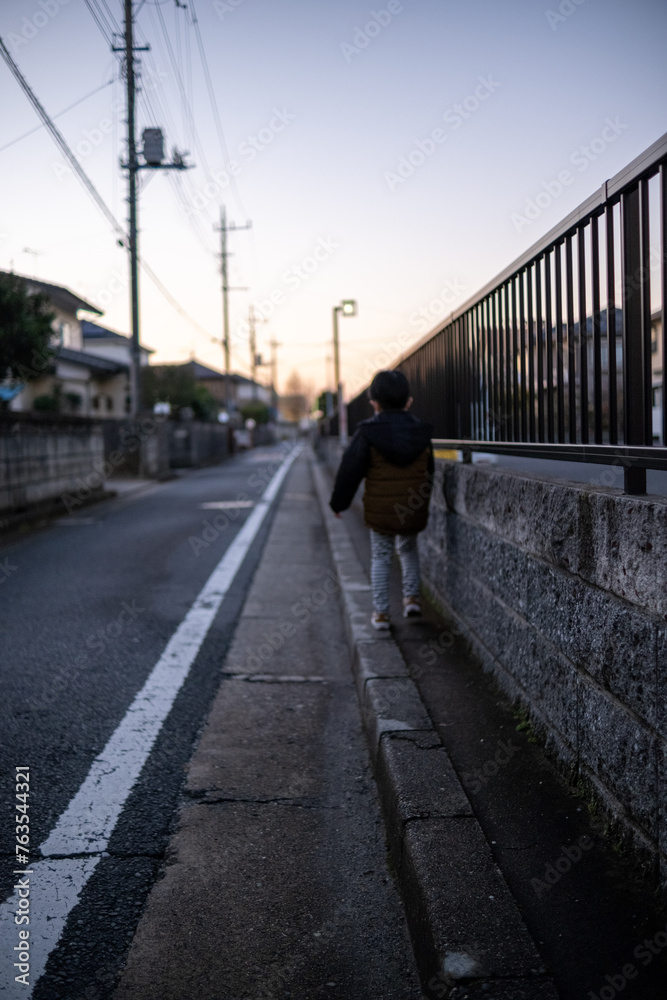 夕方の街の小道を散歩する子供