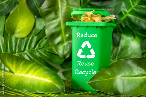 A miniature green garbage bin among beautiful wild greenery with three main words of ecology consumption. lettering slogan Reduce Reuse Recycle. Typographic zero waste, Go green icon