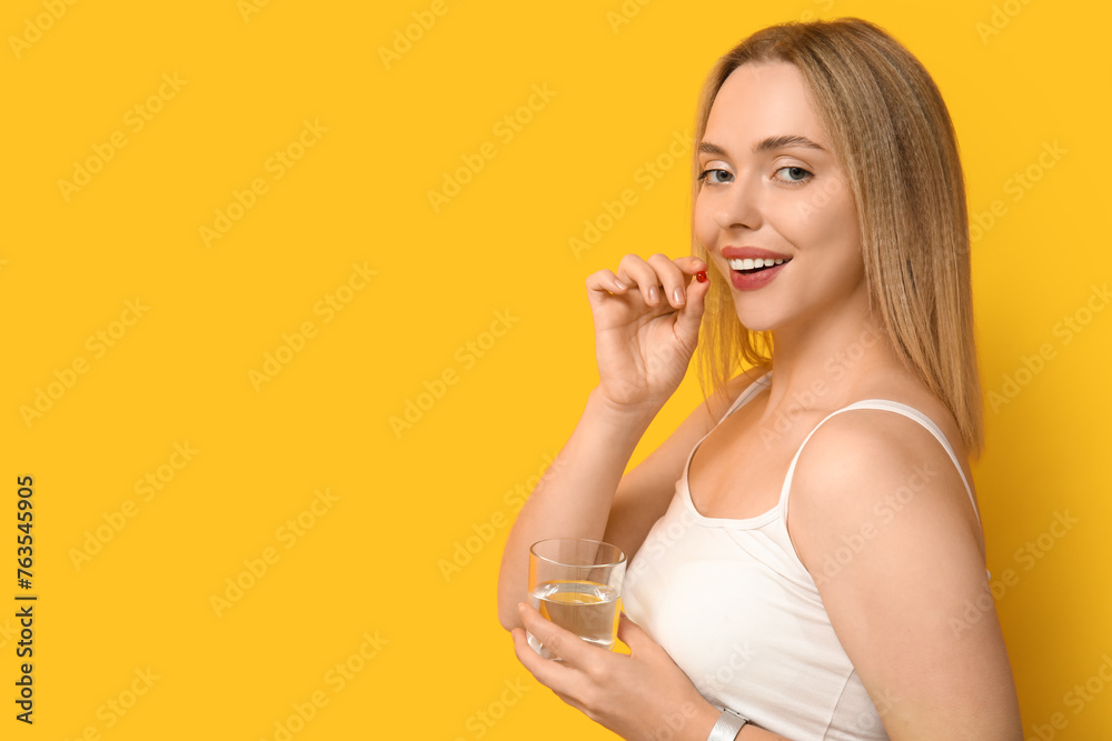 Young woman with vitamin A pills on yellow background Young woman with vitamin A pills on yellow background