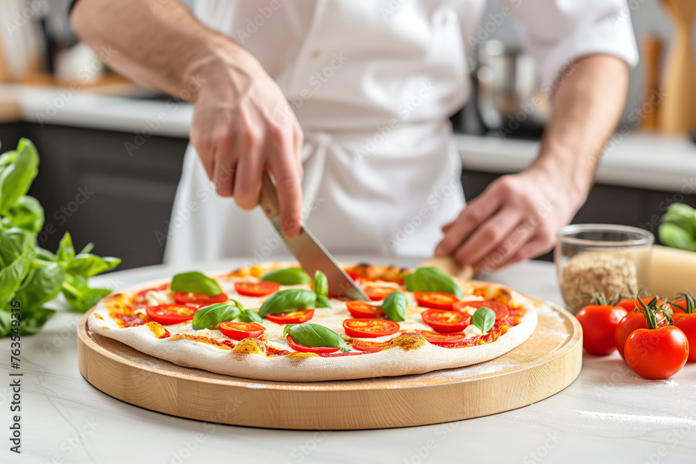 Chef cutting pizza with knife on wooden board in kitchen, close up
