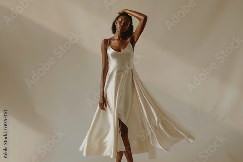 A model wears an off-white satin slip dress with shoulder straps photo