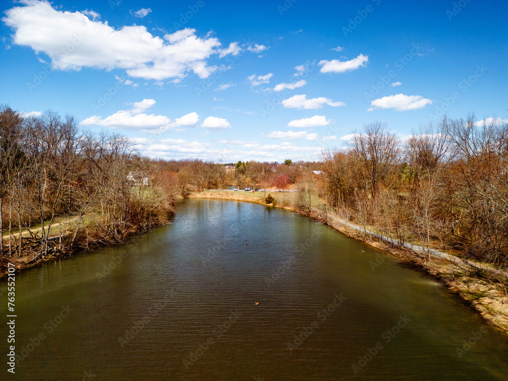 Aerial drone view of river and bright blue sky with clouds. 