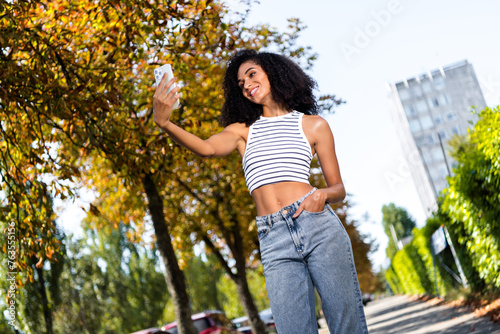 Photo of stunning cheerful girl wearing striped clothes speaking online video call walk in park cityscape background